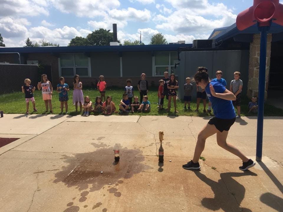 Person in blue shirt and shorts preparing to launch a bottle rocket