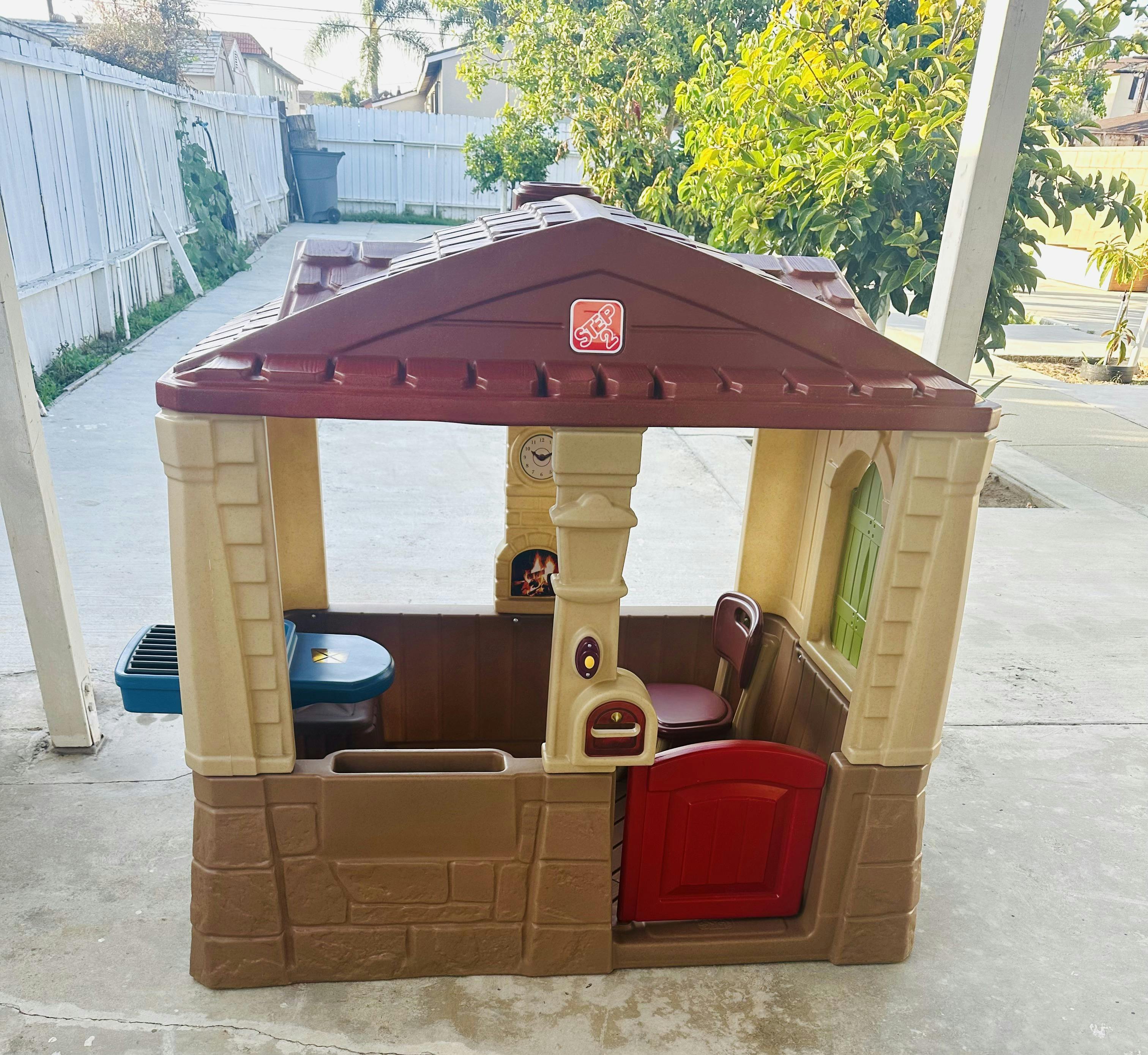 Plastic playhouse with a brown roof and tan walls
