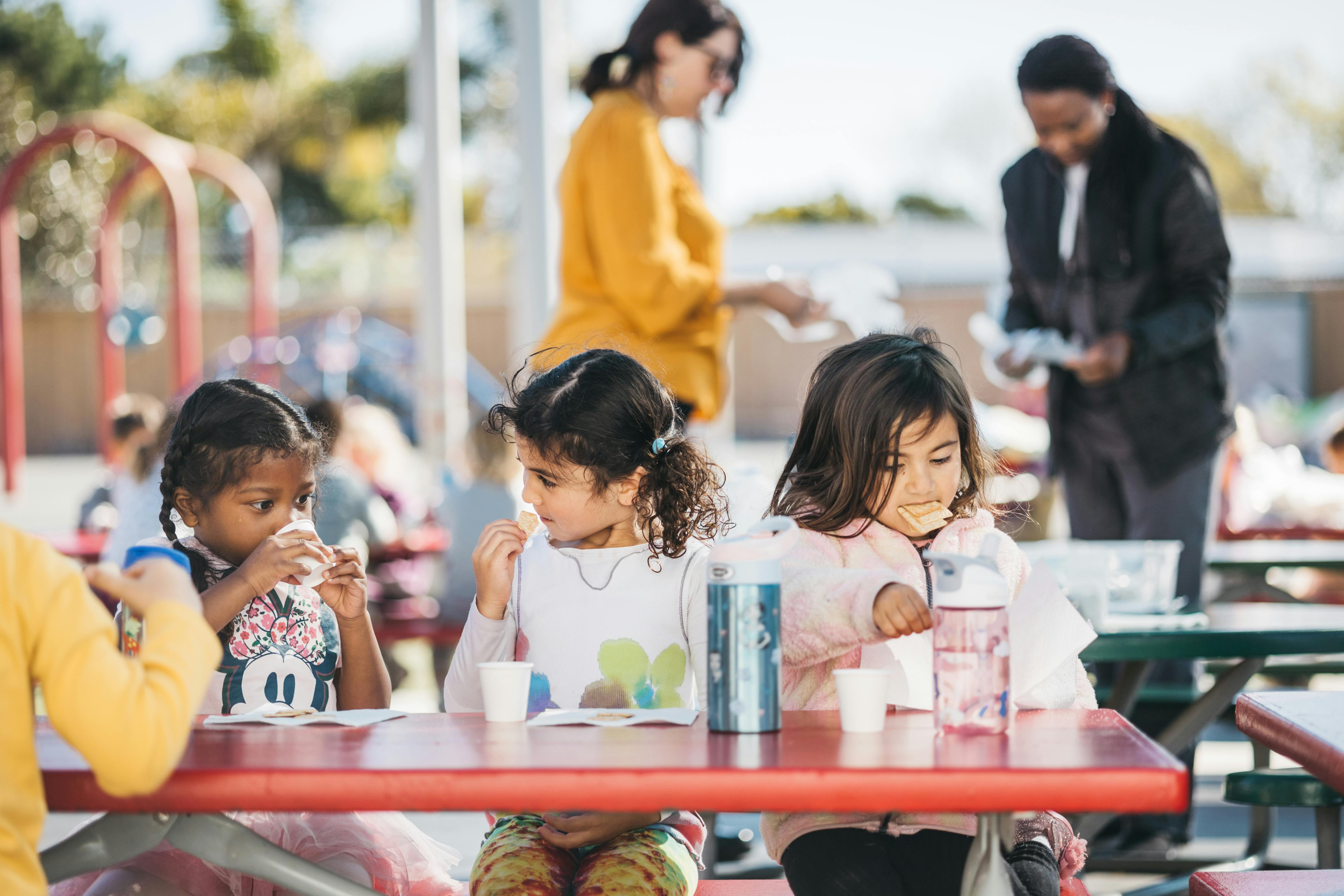 Children sitting at a table with adults in the background