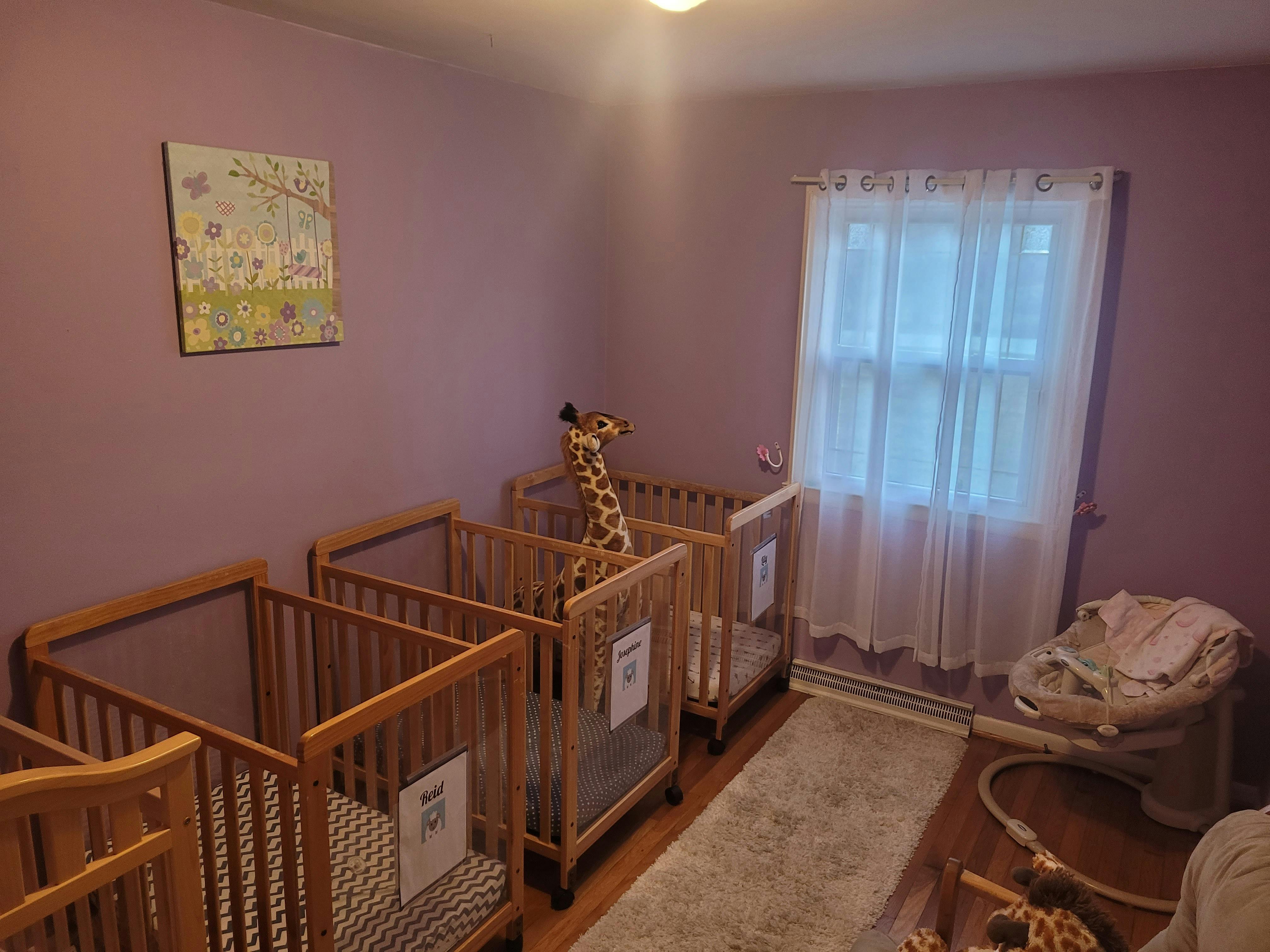 Three wooden cribs with signs on the side for different children