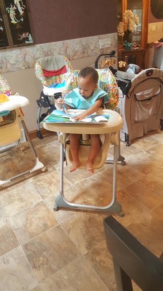 Child in a high chair looking at a book