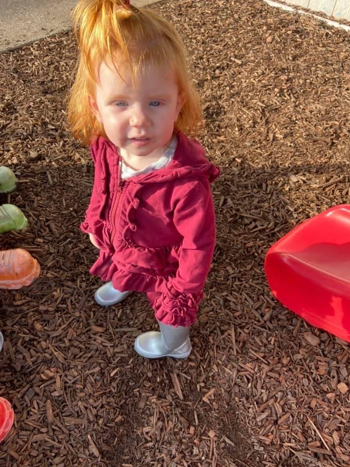 Child in a red jacket standing on wood chips
