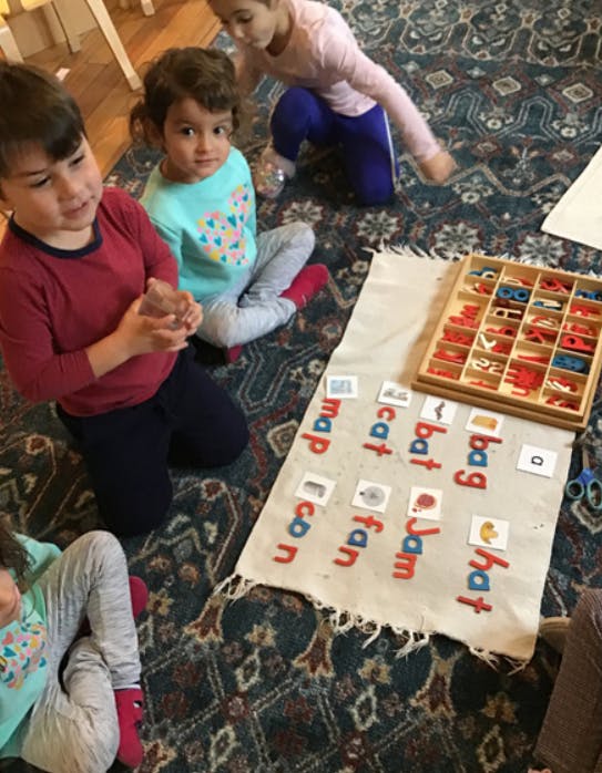 Children on a rug with a mat displaying words and letters