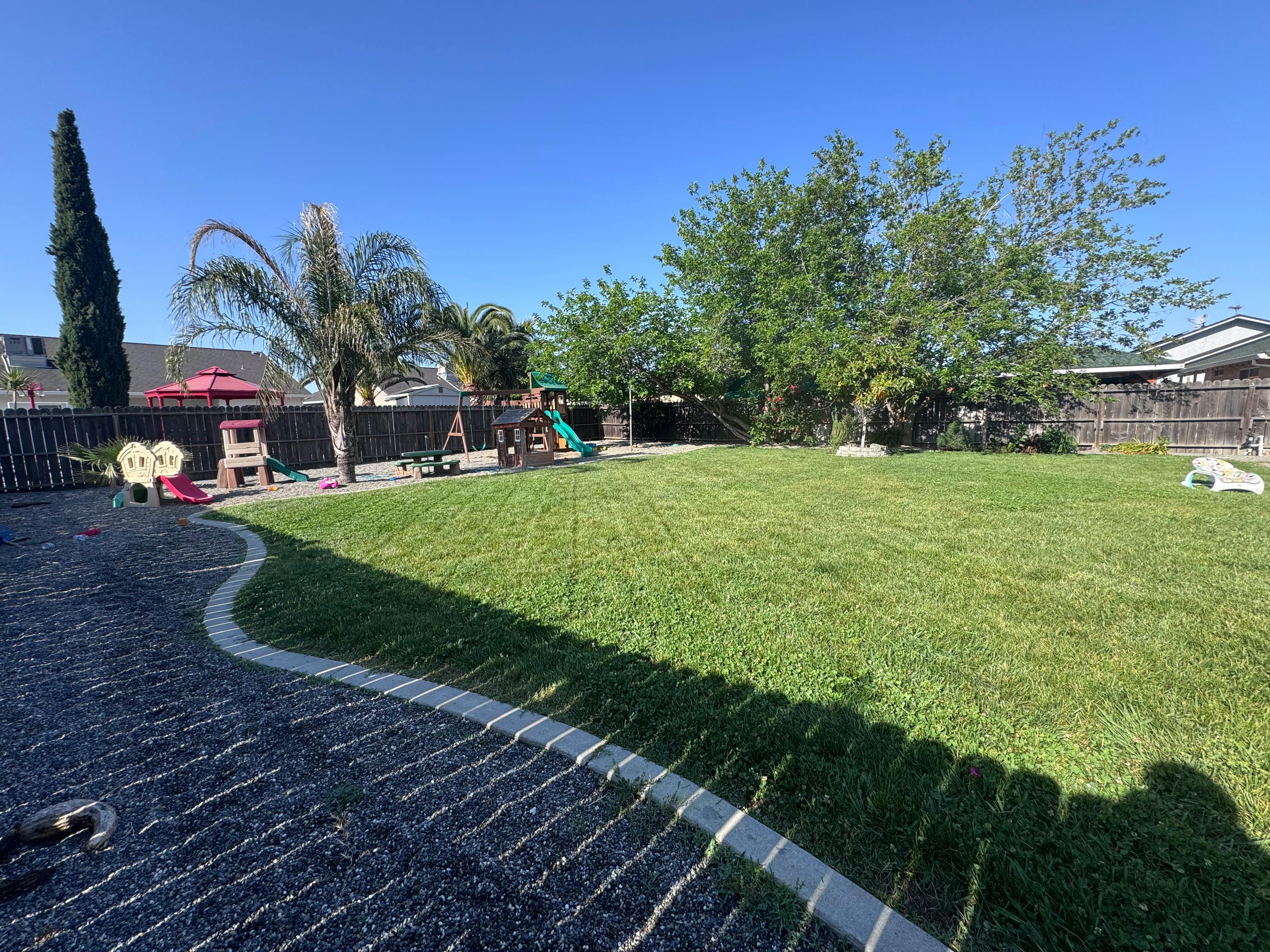 Backyard with a large grassy area and playground equipment