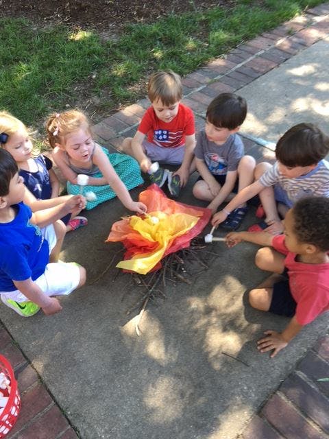 Children sitting around a pretend campfire with marshmallows on sticks
