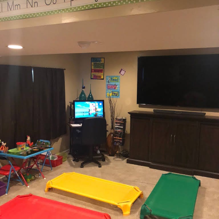 Playroom with small cots, a child's table, and a large television