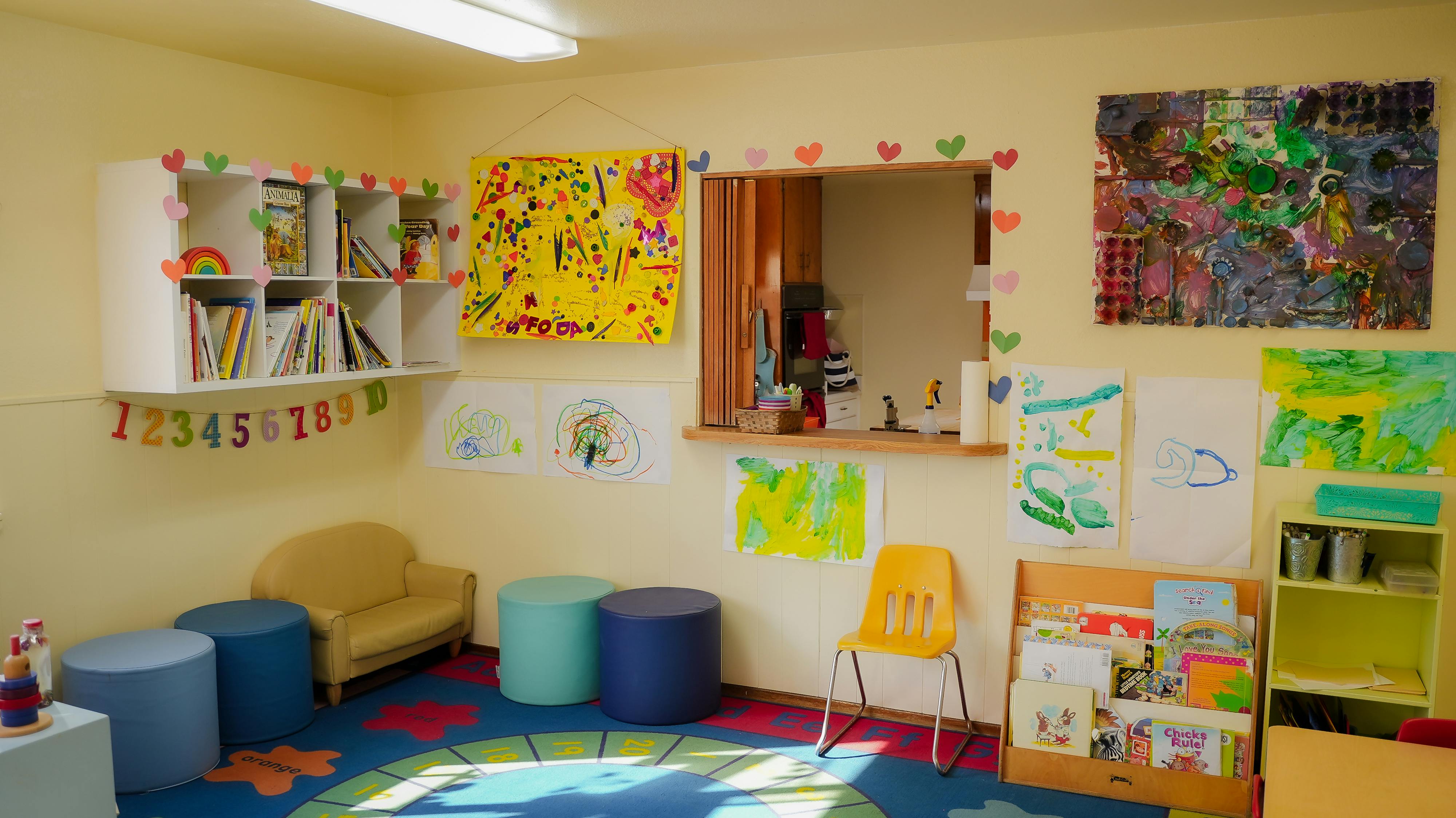 Colorful classroom with children's artwork, bookshelves, and seating