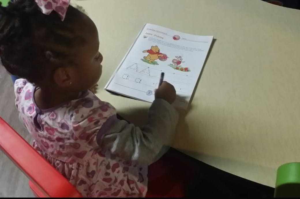 Child drawing in a book with a coloring book