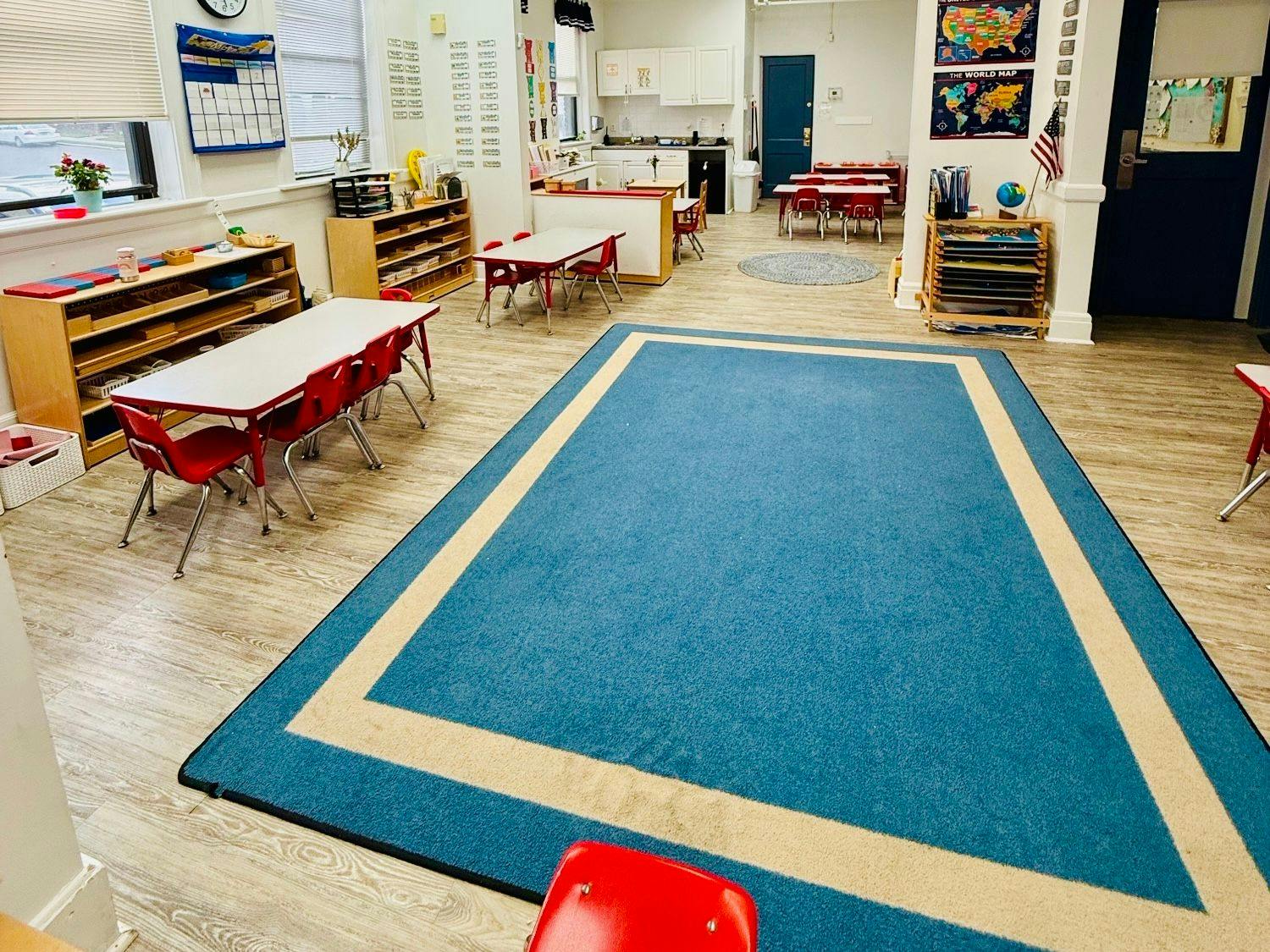 Classroom with child-sized tables and chairs and a blue rug