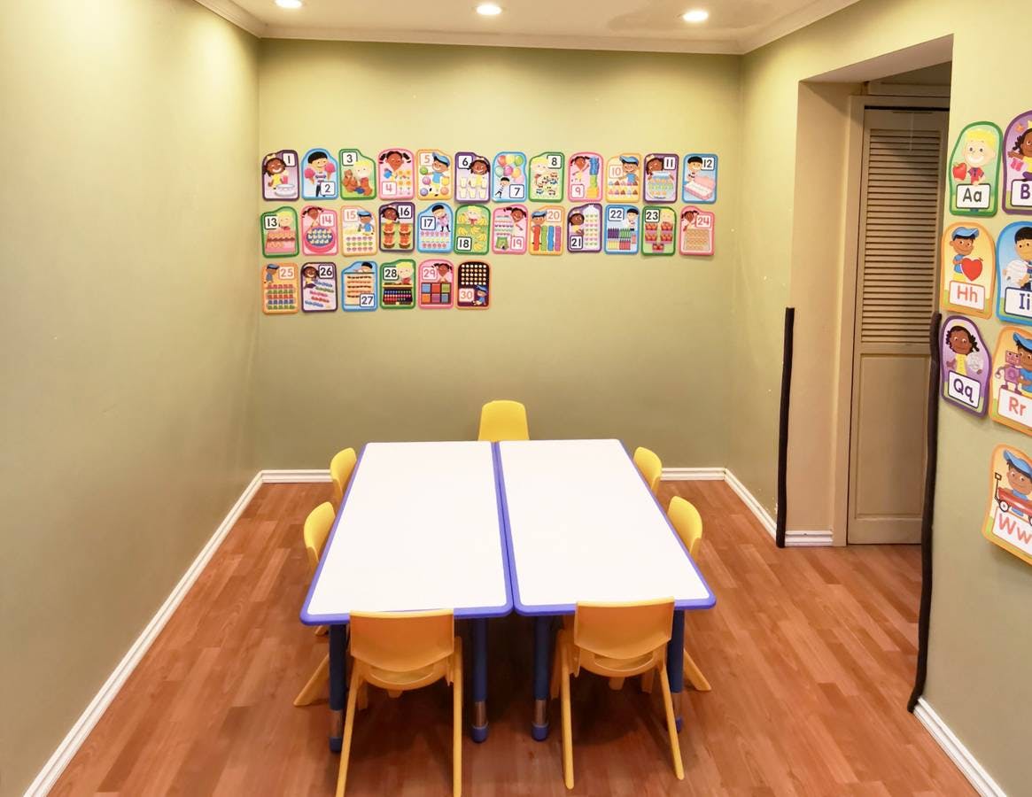 Classroom with two tables and yellow chairs, alphabet cards on the wall