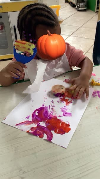 Child painting on paper with red and purple paint