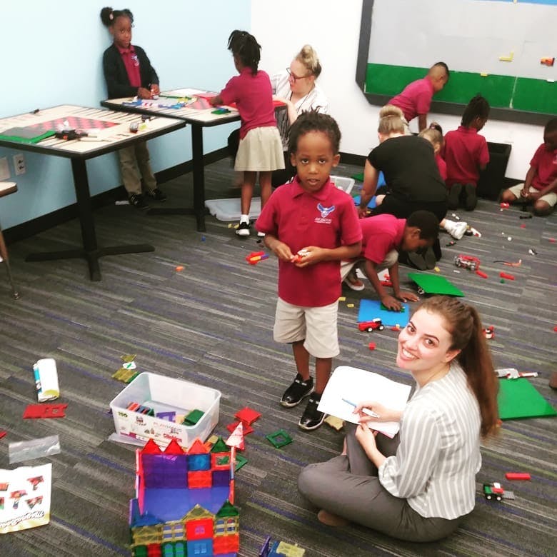 Adult and children playing with building blocks in a classroom