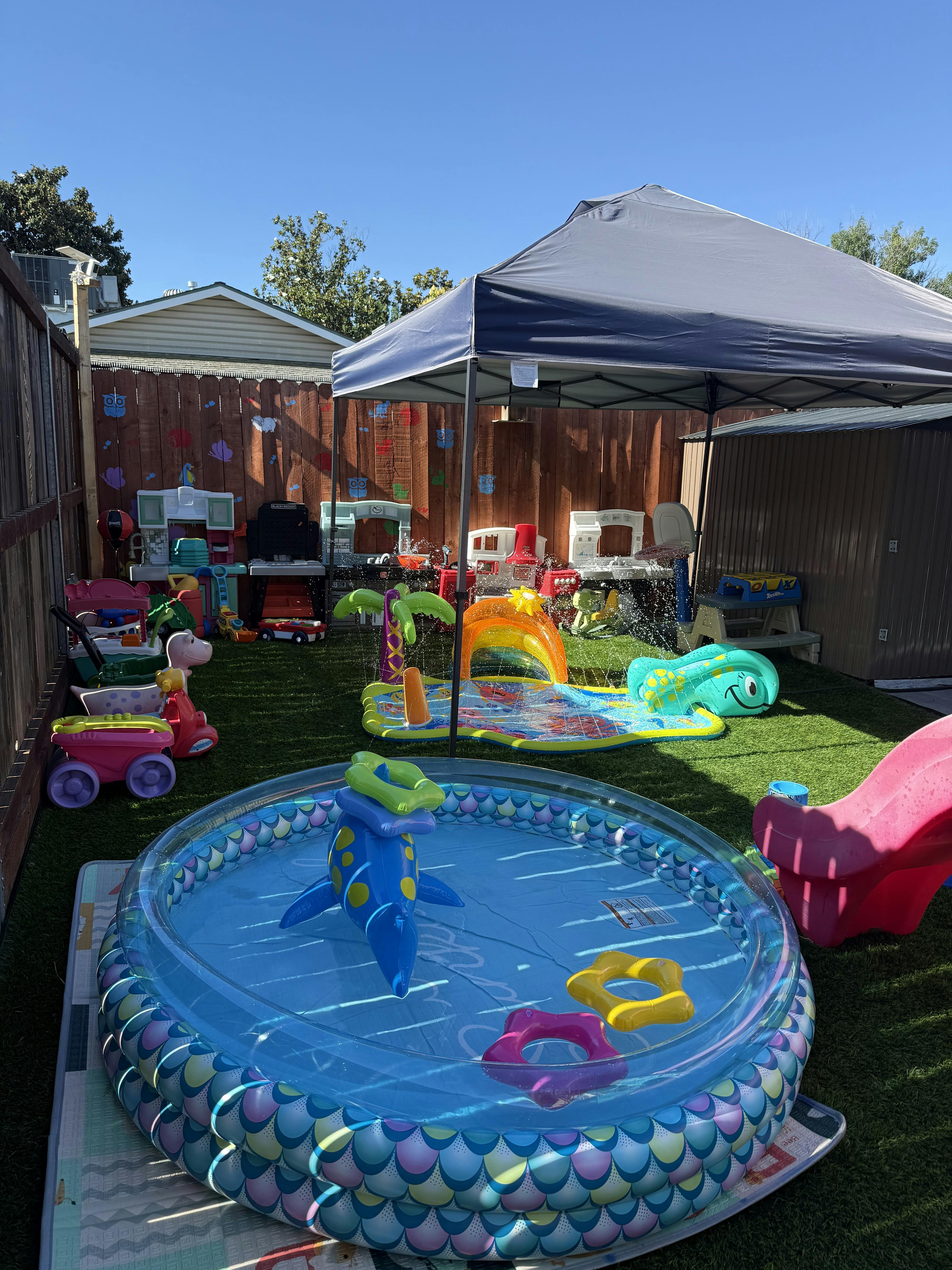 Inflatable pool and sprinkler water toys in a backyard play area