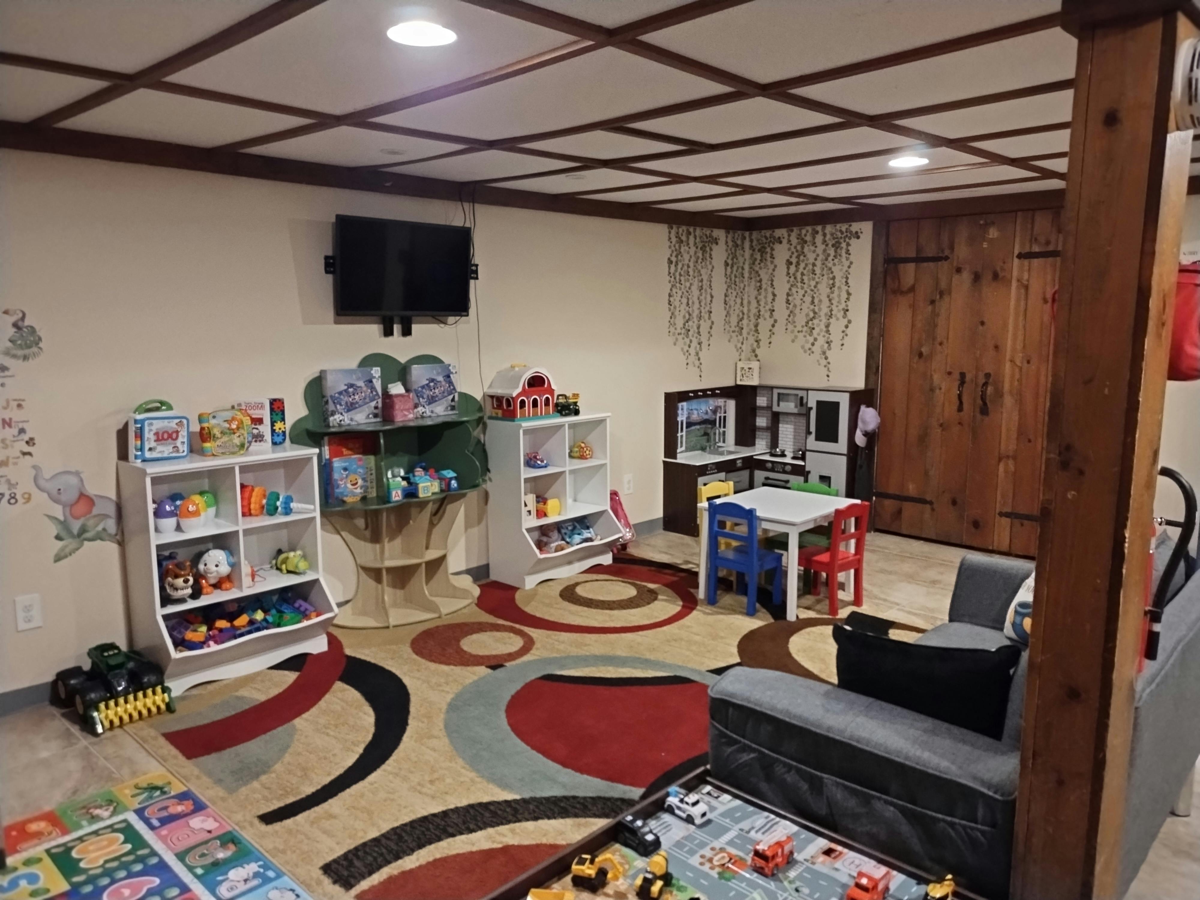 Playroom with toys, shelves, small table and chairs, and a patterned rug