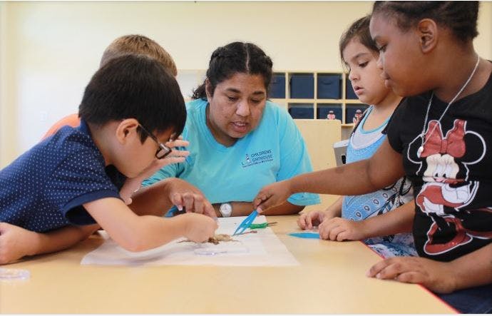Adult and three children working on a craft project at a table