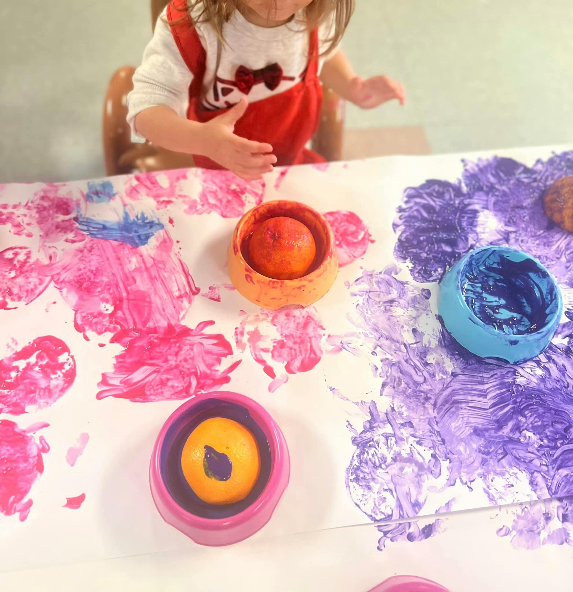 Child finger painting with pink and purple paint