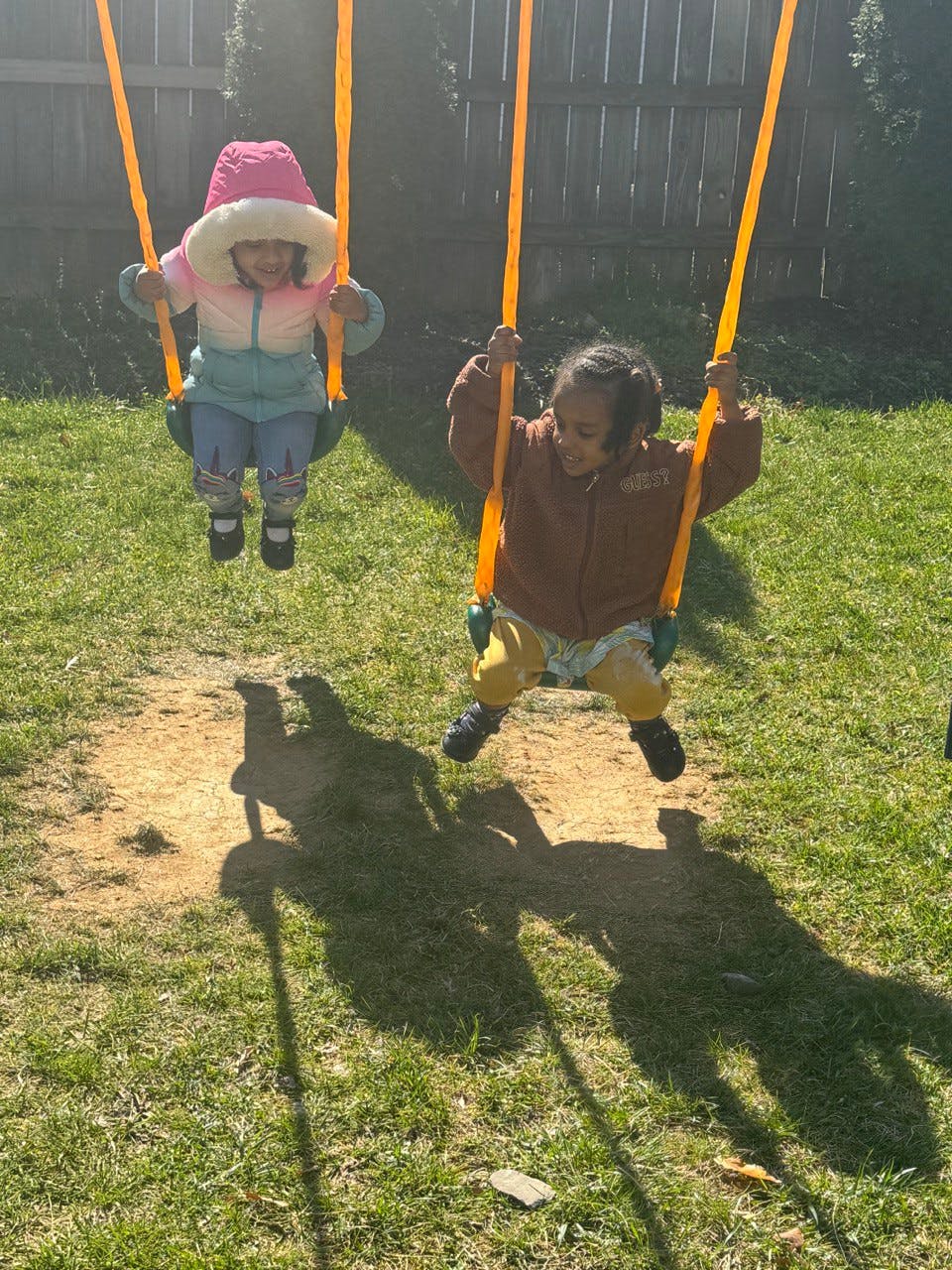 Two children on swings in a grassy area