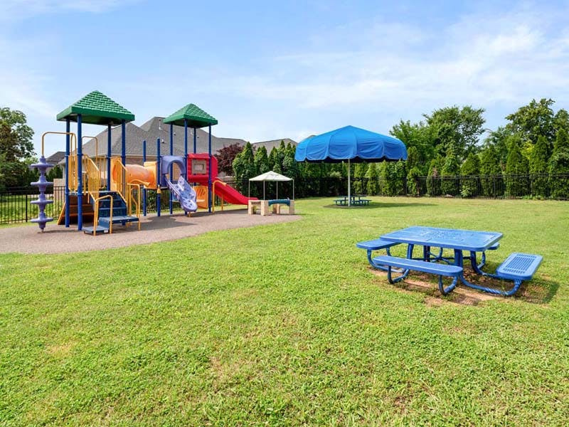 A children's playground with slides, swings, and climbing structures next to a picnic table