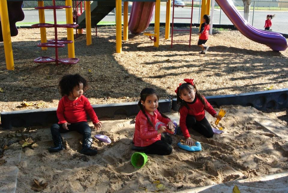 Three children playing in a sandbox on a playground