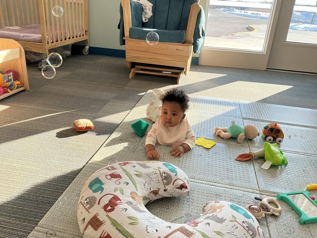 Baby on a playmat surrounded by toys and bubbles