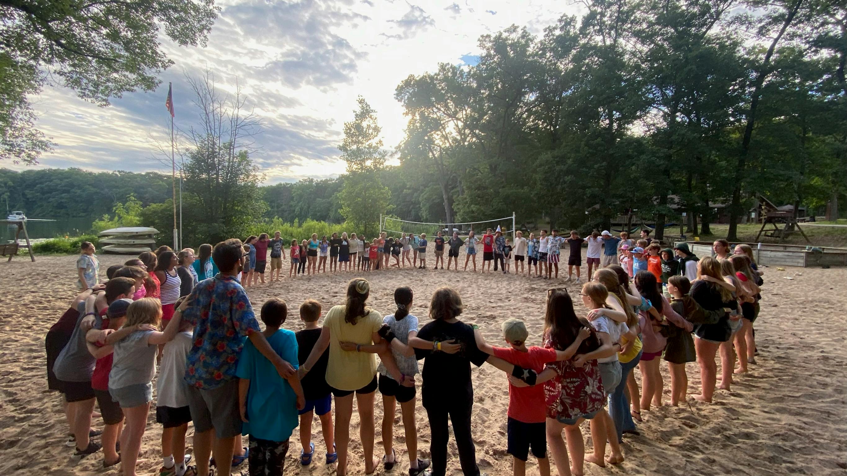 Group of people and children standing in a circle on a sandy beach