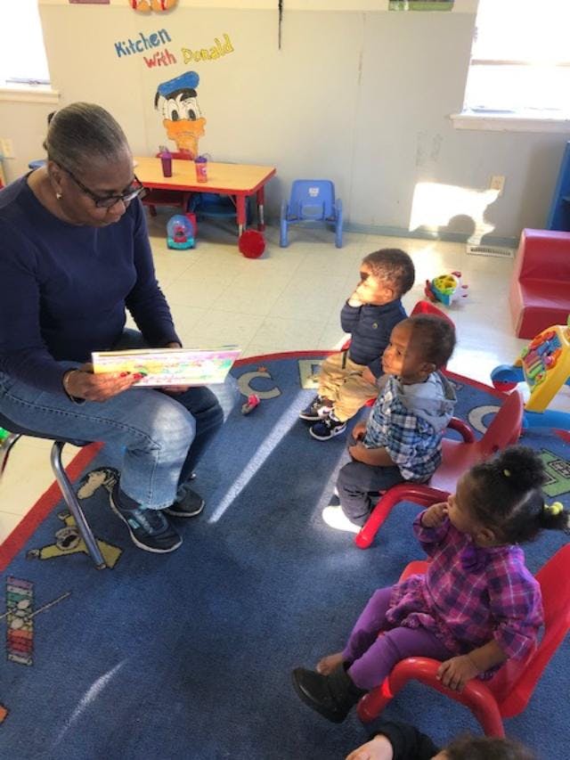 Person reading a book to children in a classroom
