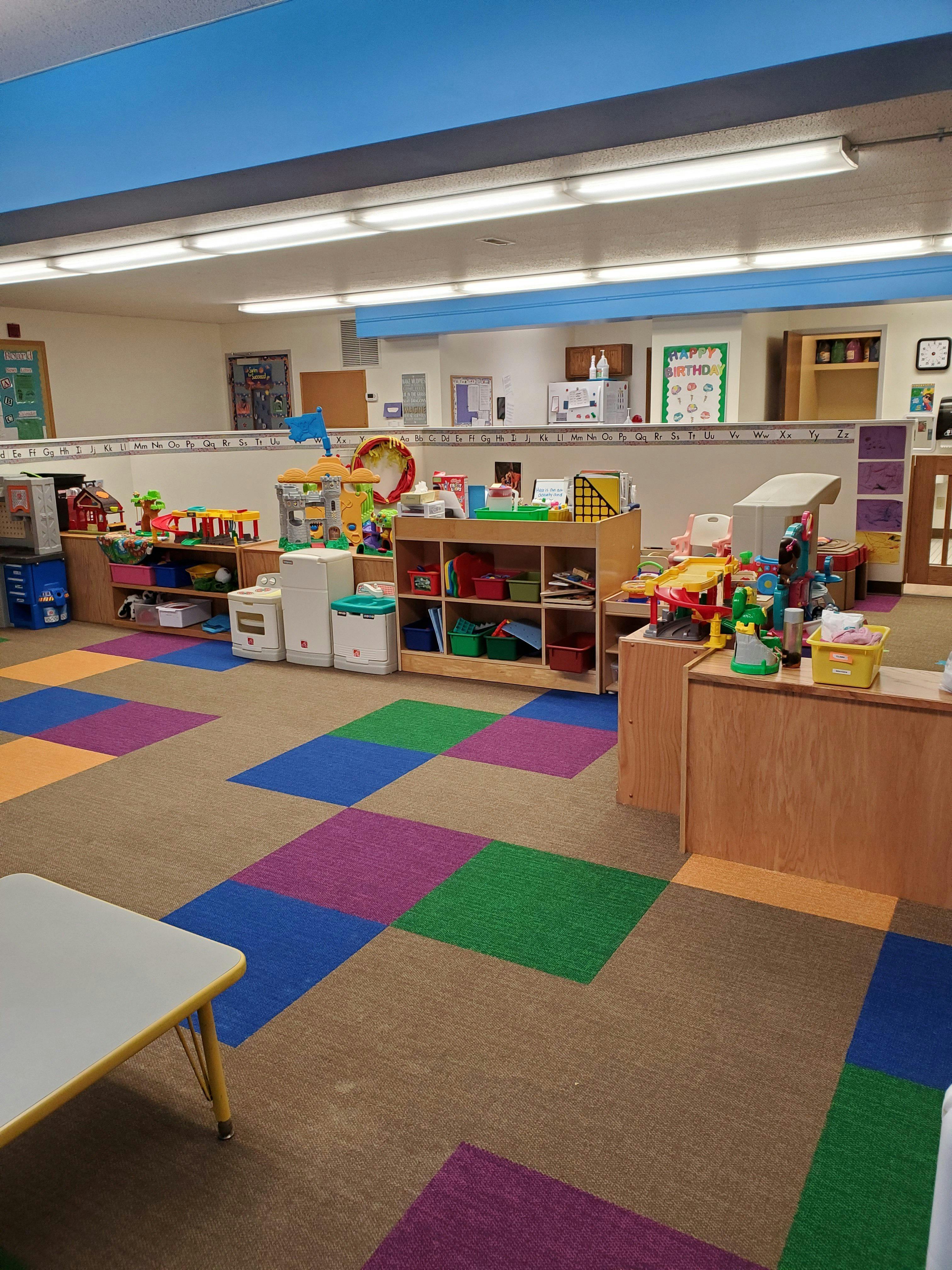 Classroom with colorful floor tiles and shelves of toys