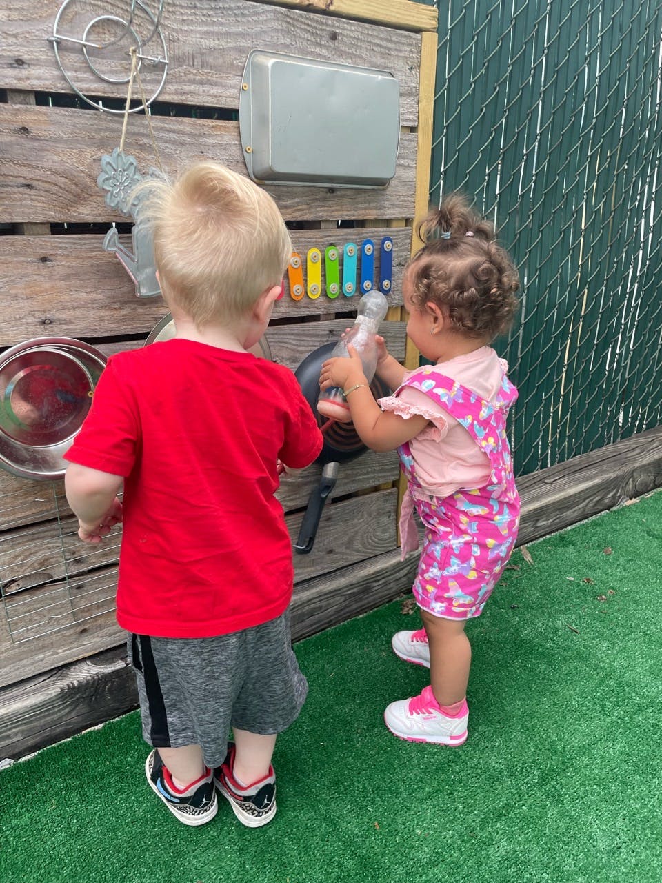 Two children playing with musical instruments on a wooden wall