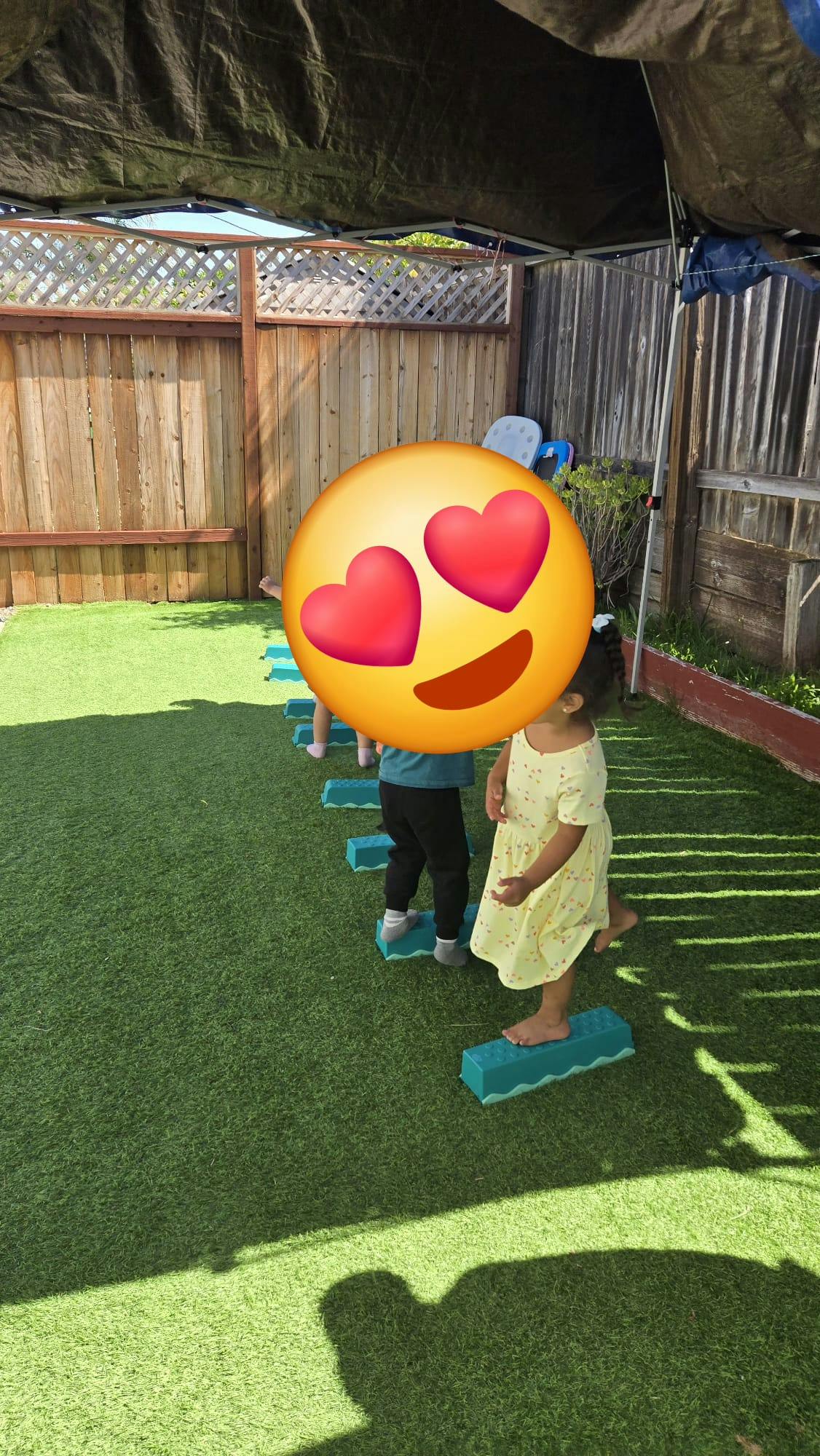 Children walking on blue balance beams on artificial grass