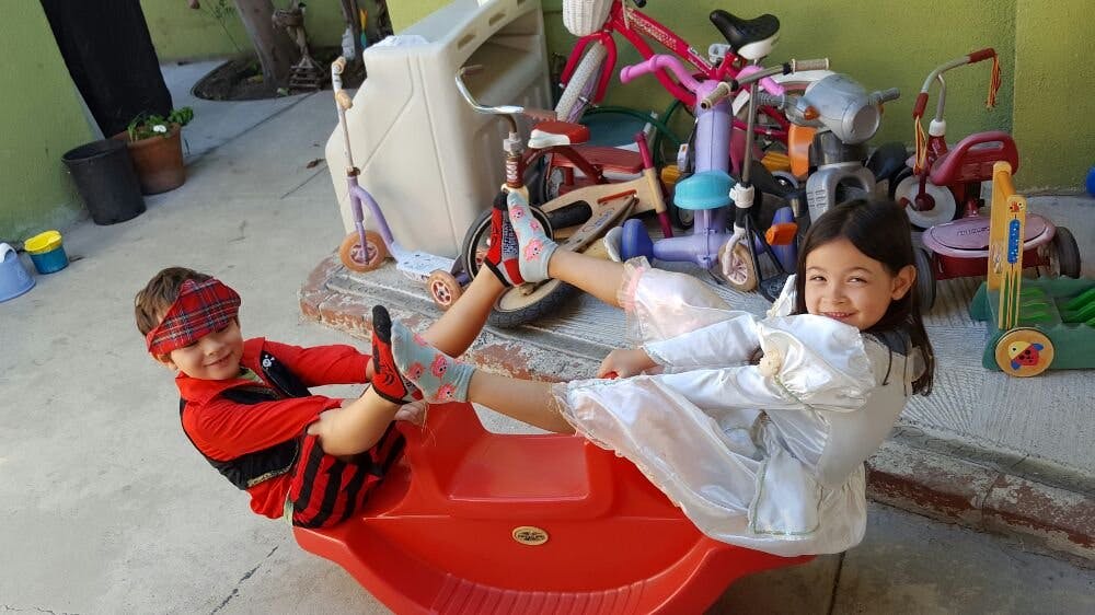 Two children playing on a red seesaw toy