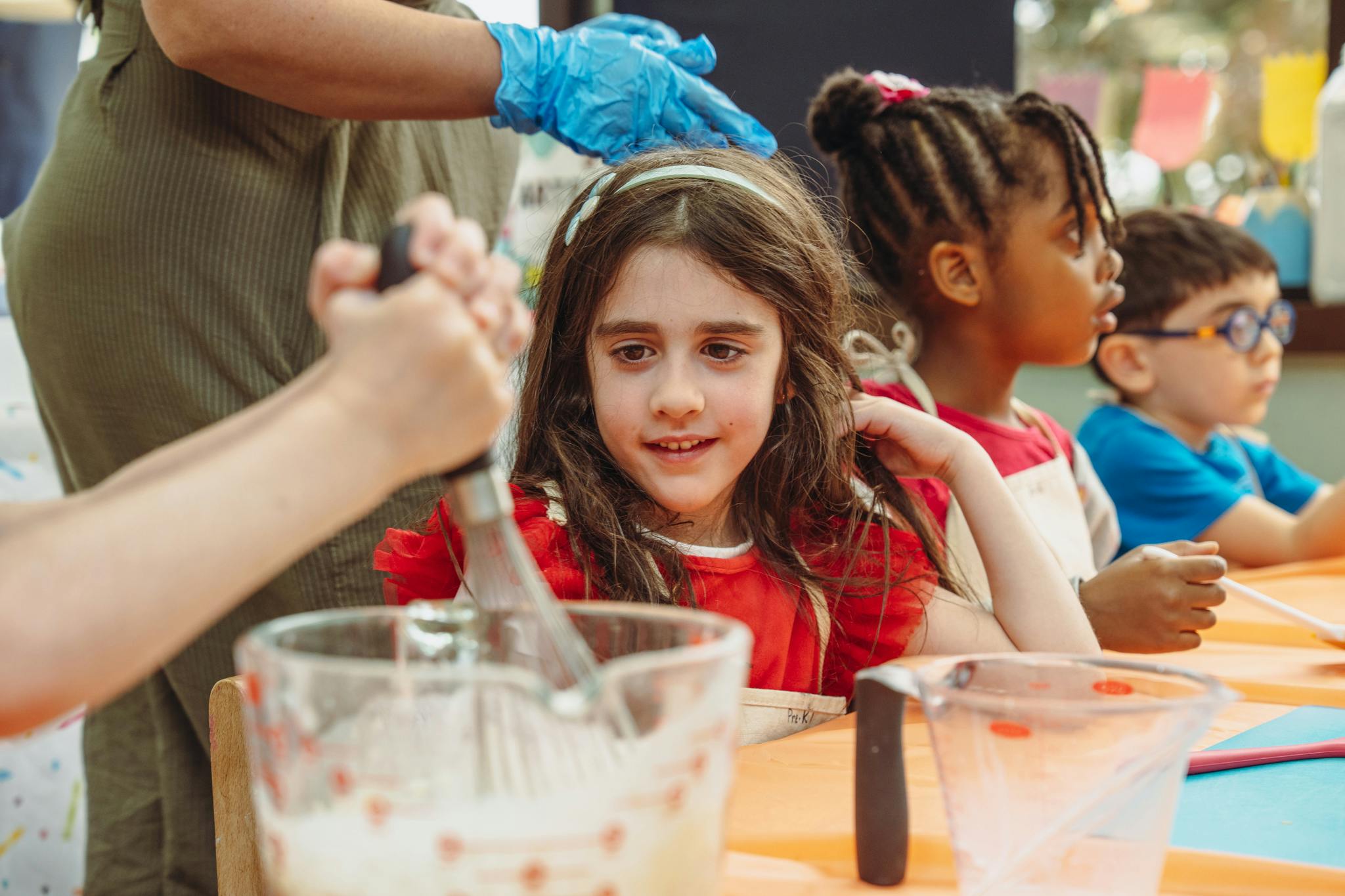 Child mixing ingredients in a bowl with other children nearby