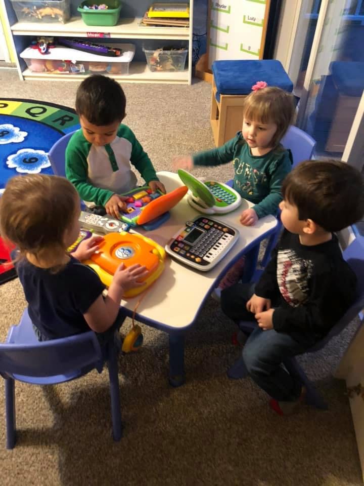 Four children playing with toys at a small table