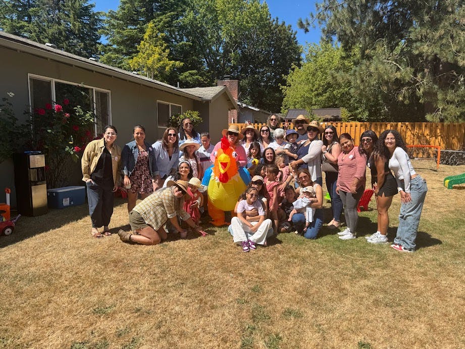 Group of people and children posing outdoors with a colorful inflatable toy