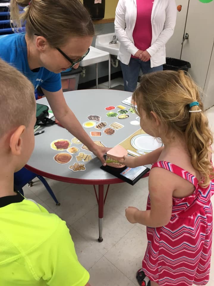 Adult and two children at a table with food cutouts