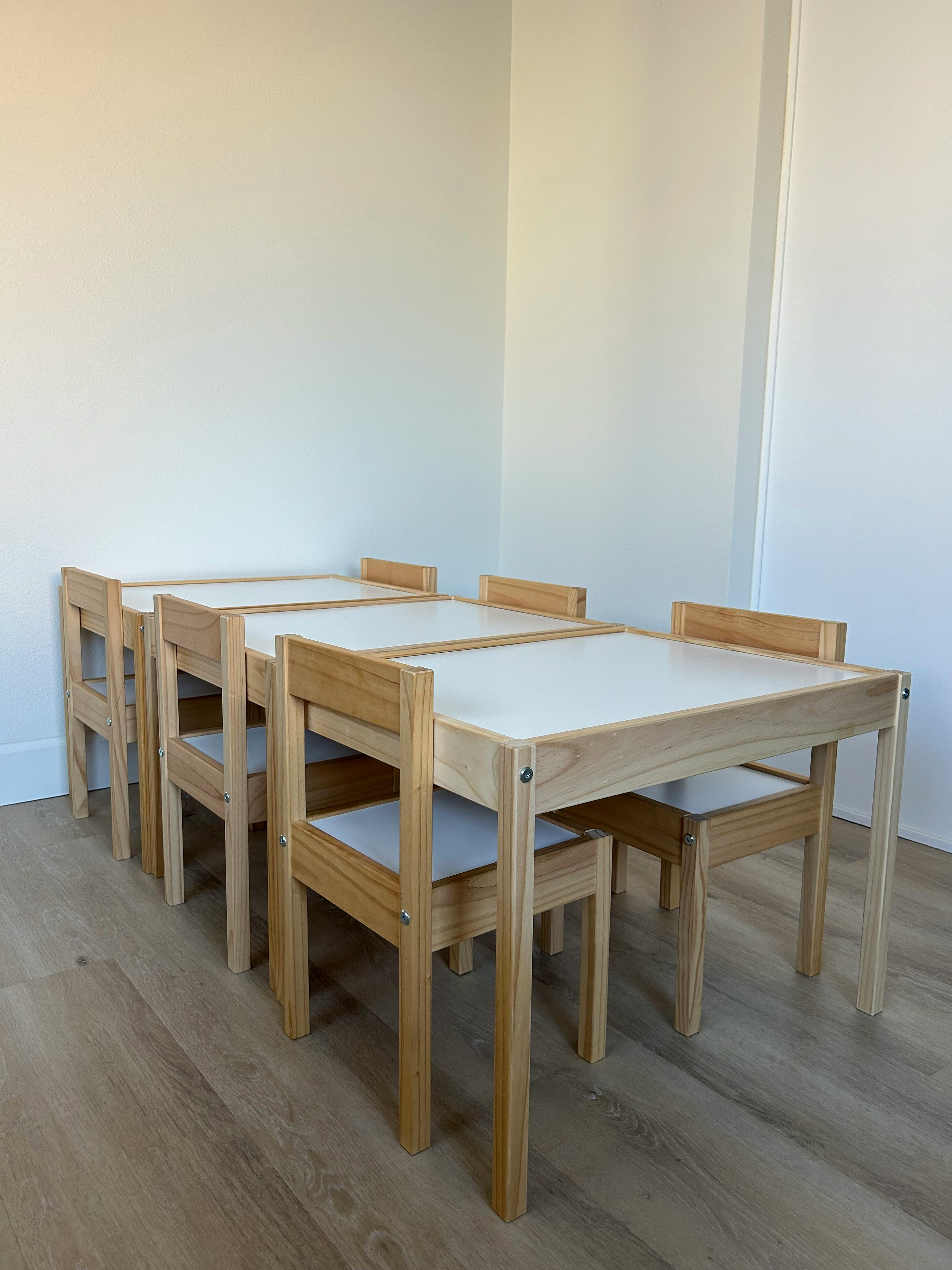 Four wooden tables with white tops and matching chairs