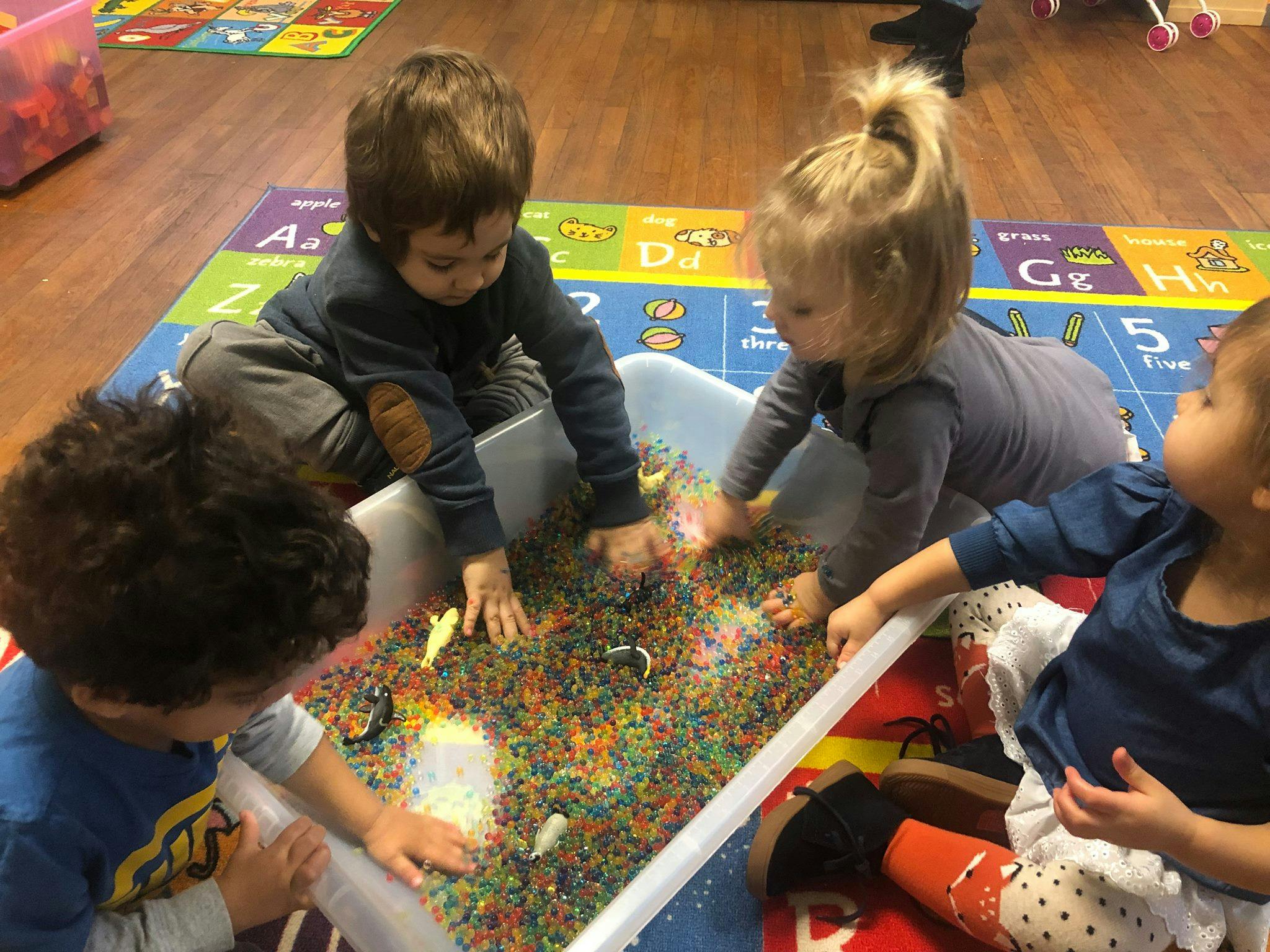 Children playing with colorful beads in a sensory bin