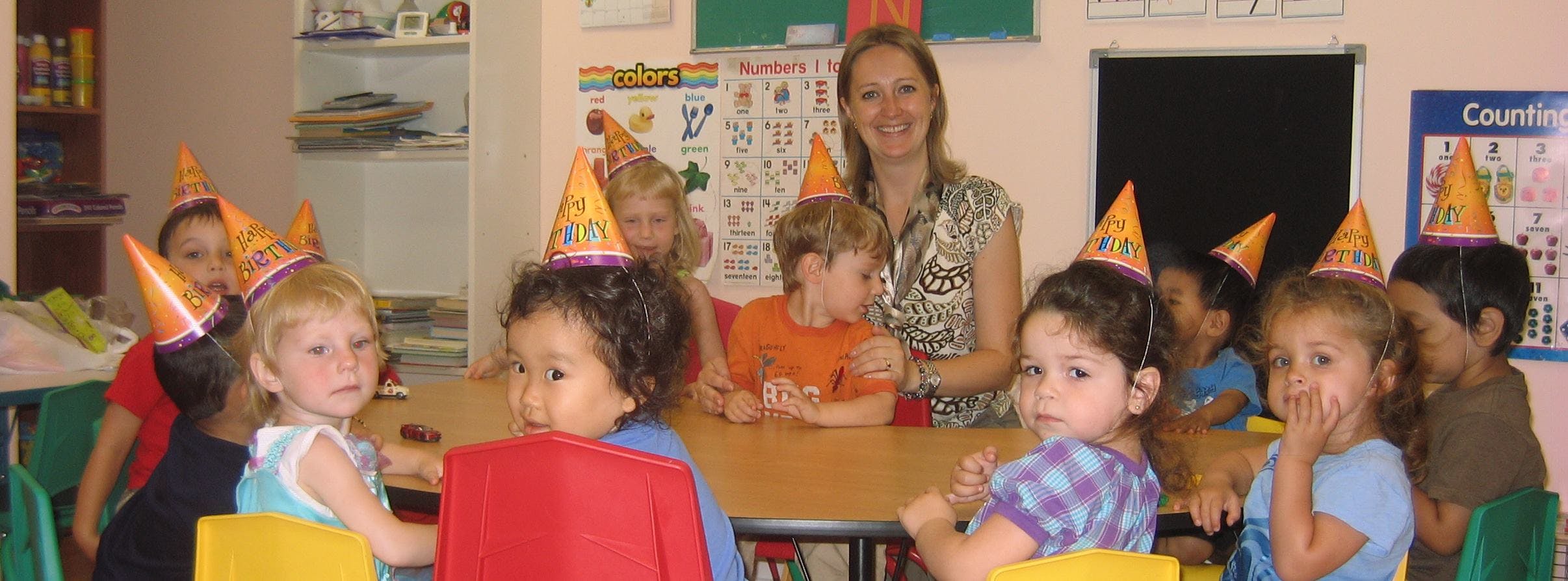 Adult and children wearing party hats in a classroom