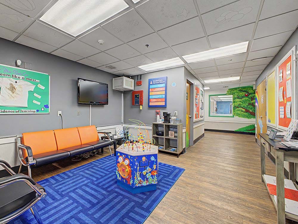 Waiting area with orange chairs, blue rug, and a children's play table