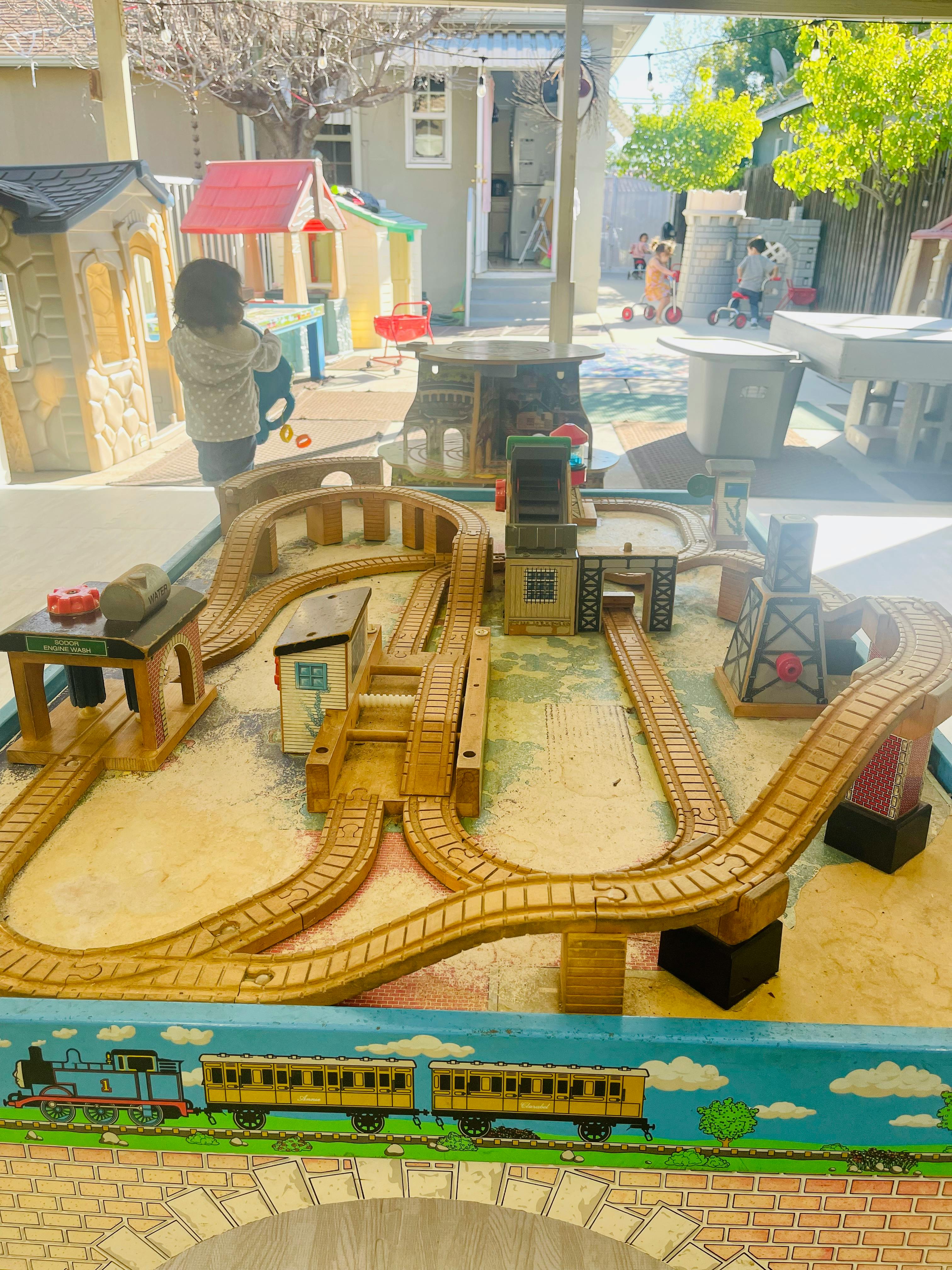 Child playing with a wooden toy train set on a table