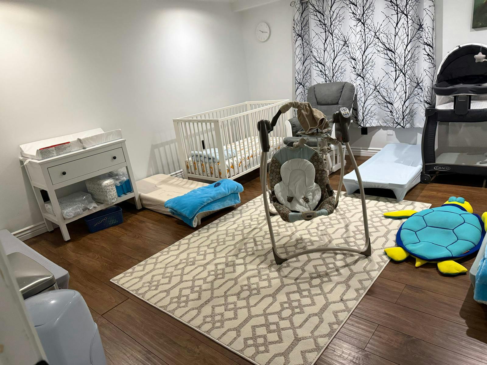 Nursery room with a crib, changing table, baby swing, and playpen