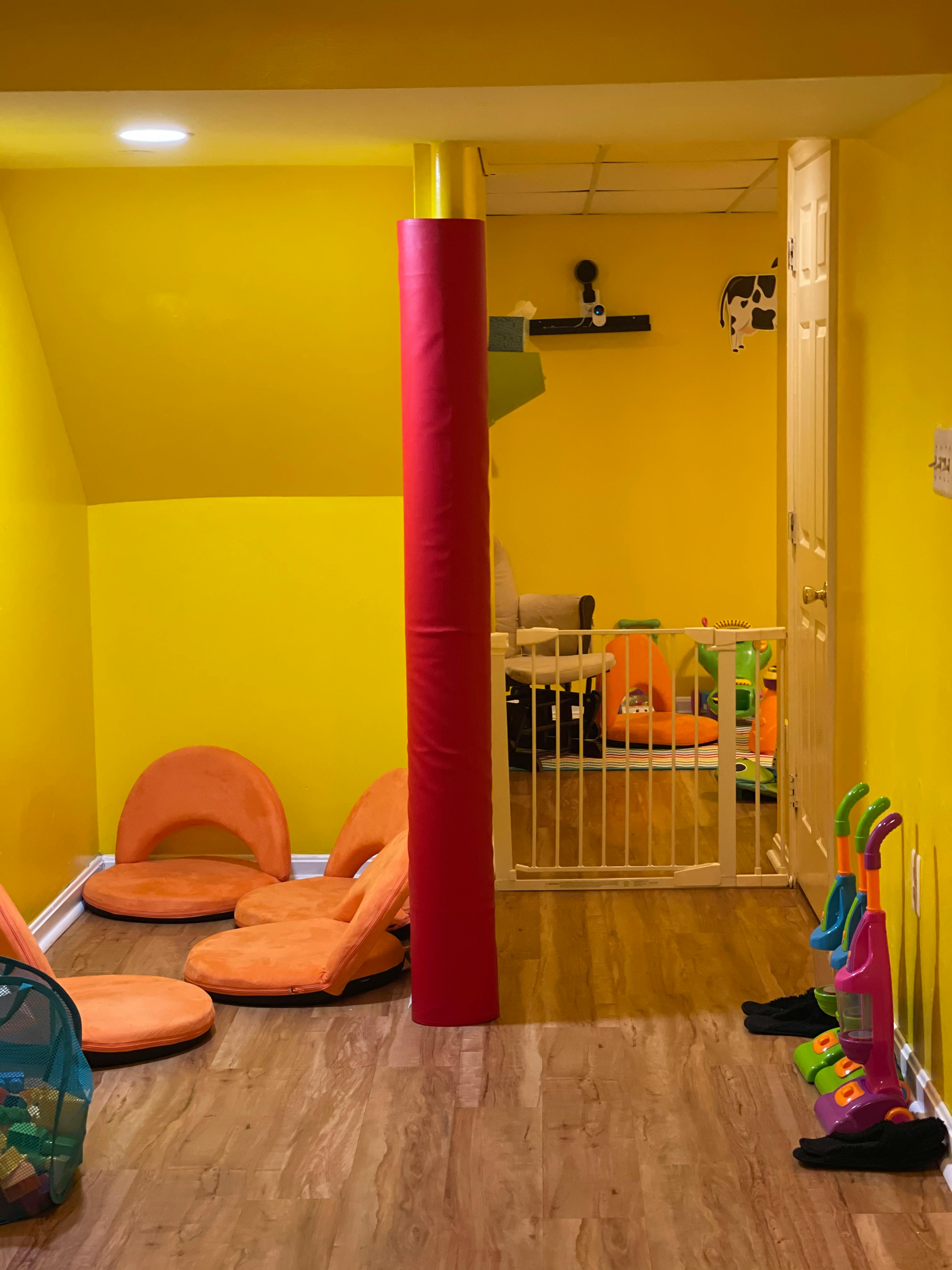 Playroom with orange floor chairs, red column, and baby gate