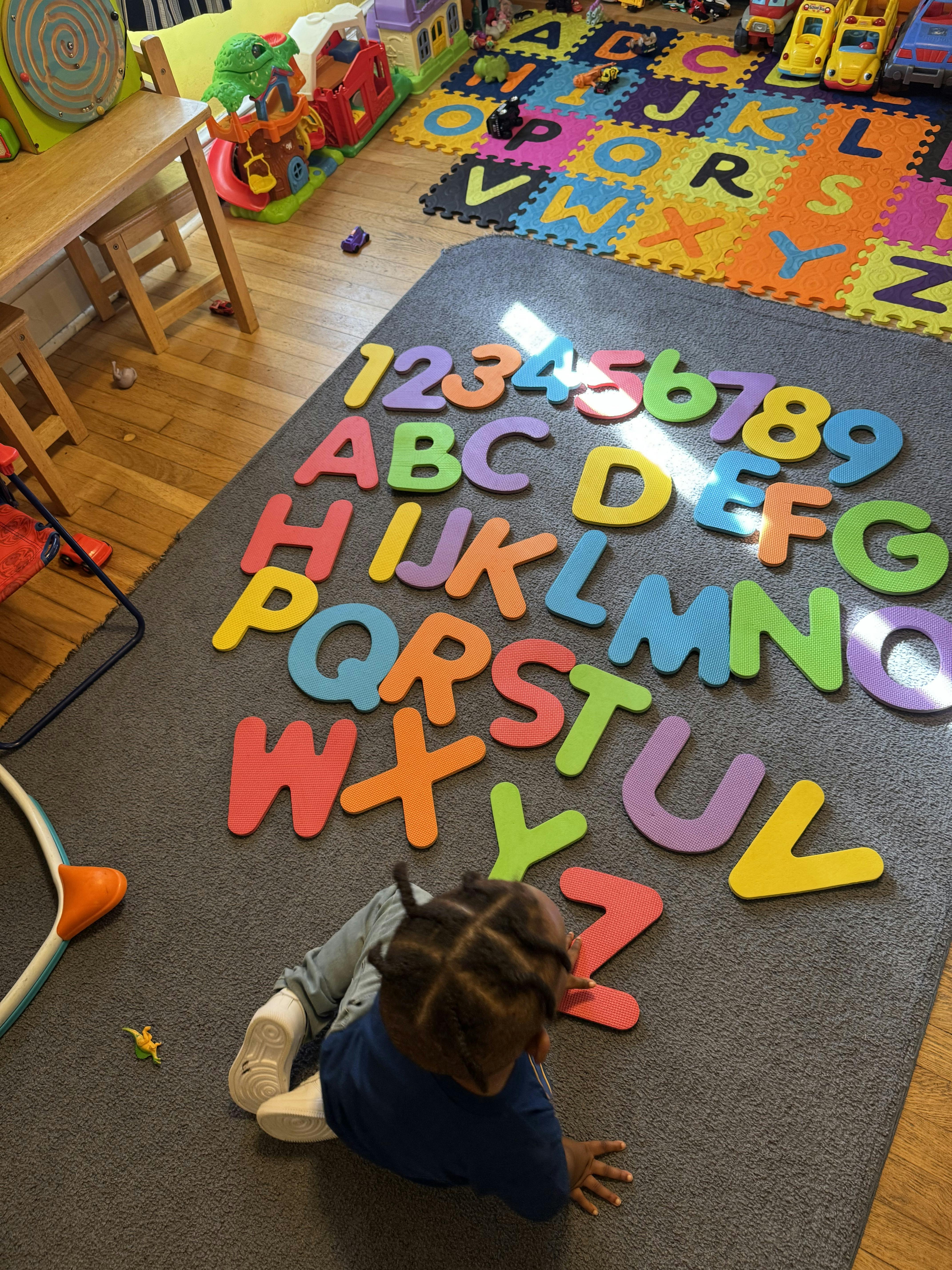 Child on floor with colorful alphabet and number cutouts