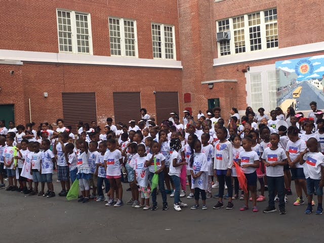 Large group of children standing in front of a brick building