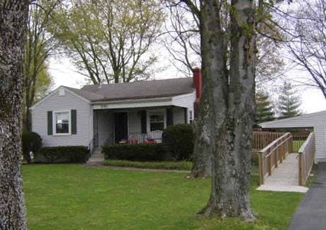 Small house with a porch and a wooden ramp leading to a side building