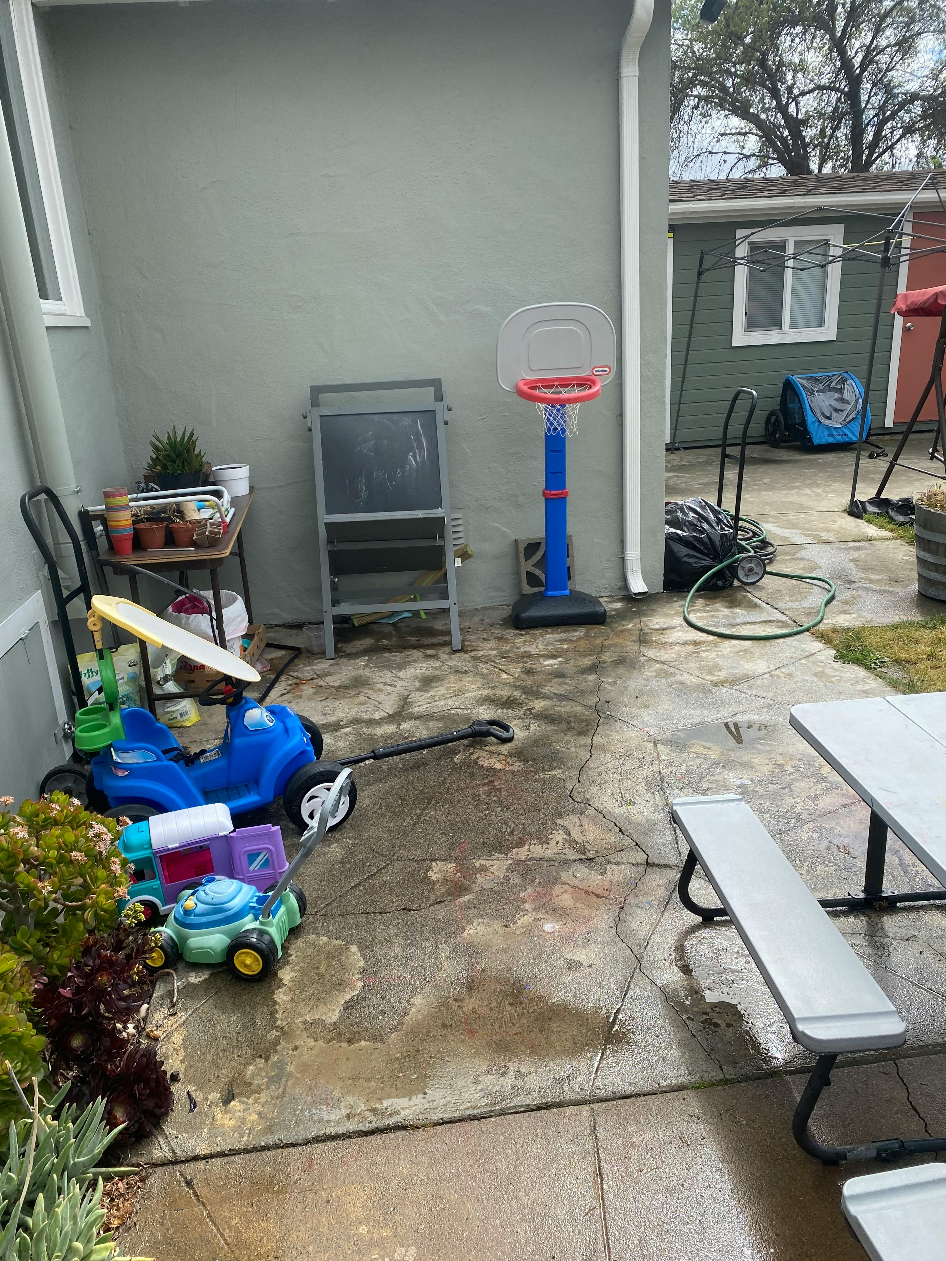 Outdoor patio with children's toys, a basketball hoop, and a picnic table