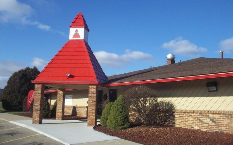 Building with a red shingled roof spire above an entrance