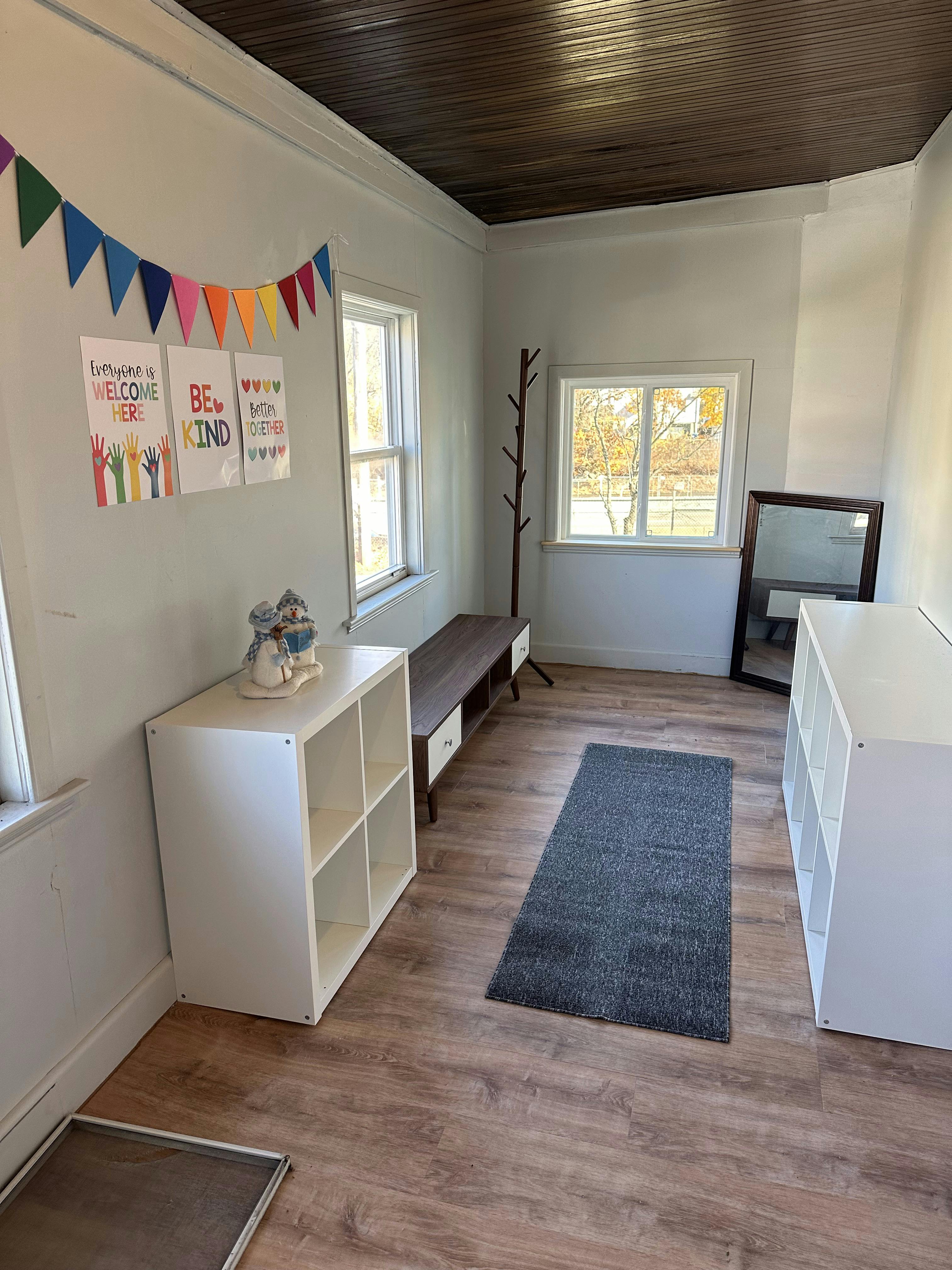 Room with wood floor, white walls, two windows, and storage shelves