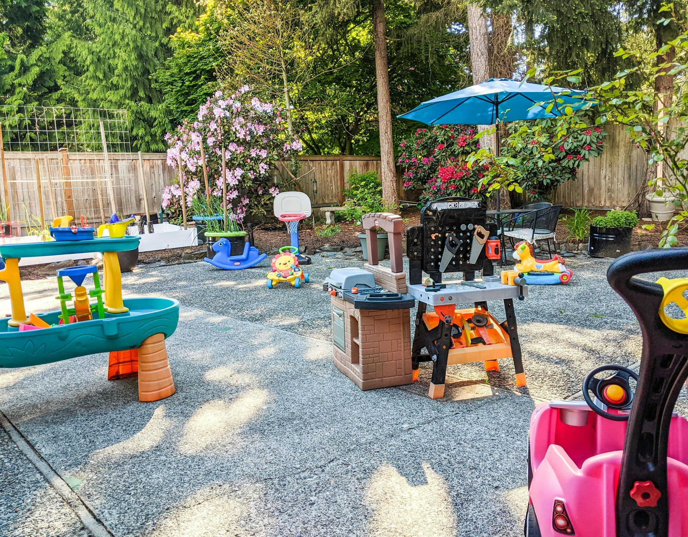 Outdoor play area with various toys including a water table and workbench