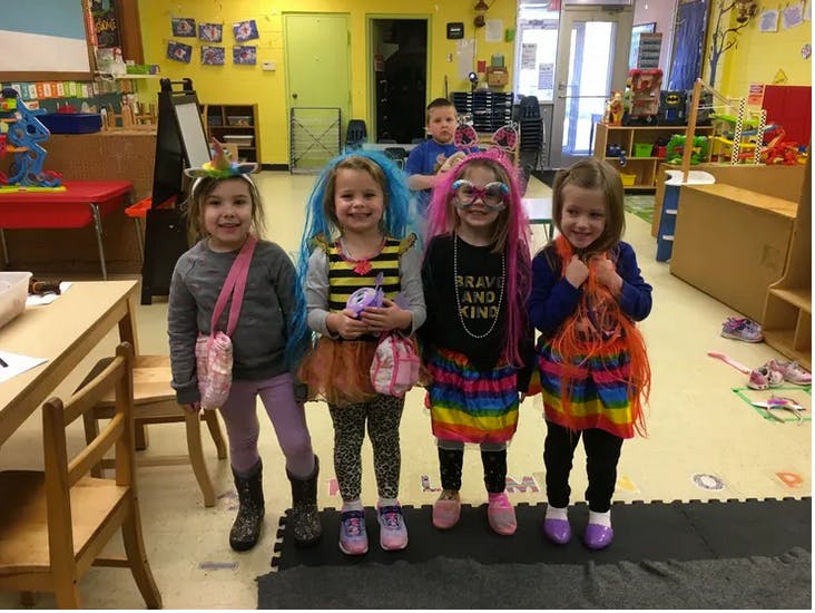 Four children in colorful costumes in a classroom
