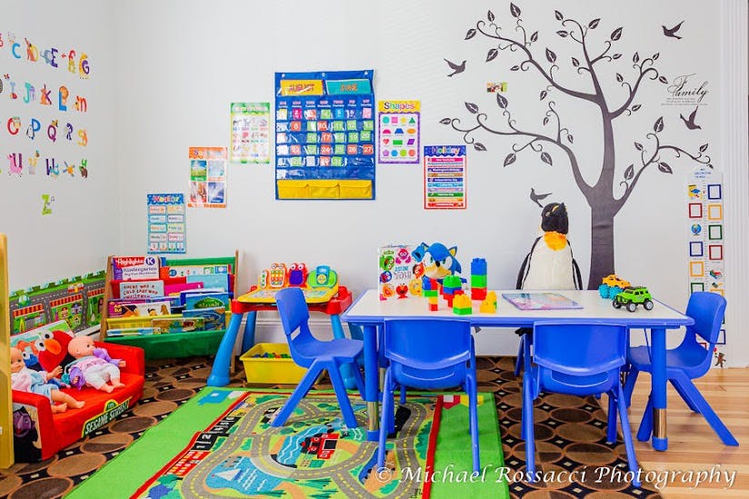 Playroom with small table and chairs, toys, and wall decorations